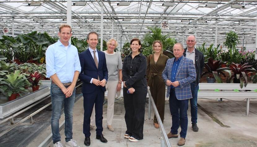 Portret in een kas van alle aanwezigen. Van links naar rechts: Martijn van Geel (eigenaar Van Geel Groep), Eddy van Hijum (minister van SZW), Adri Bom-Lemstra (voorzitter Glastuinbouw Nederland), Inge Bergsma-De Vries (directeur Drenthe Growers), Kyra Broeders (Public & Government Affairs Glastuinbouw Nederland), Ger Koopmans (voorzitter LTO Nederland) en Rien van Geel (oprichter Van Geel Groep)